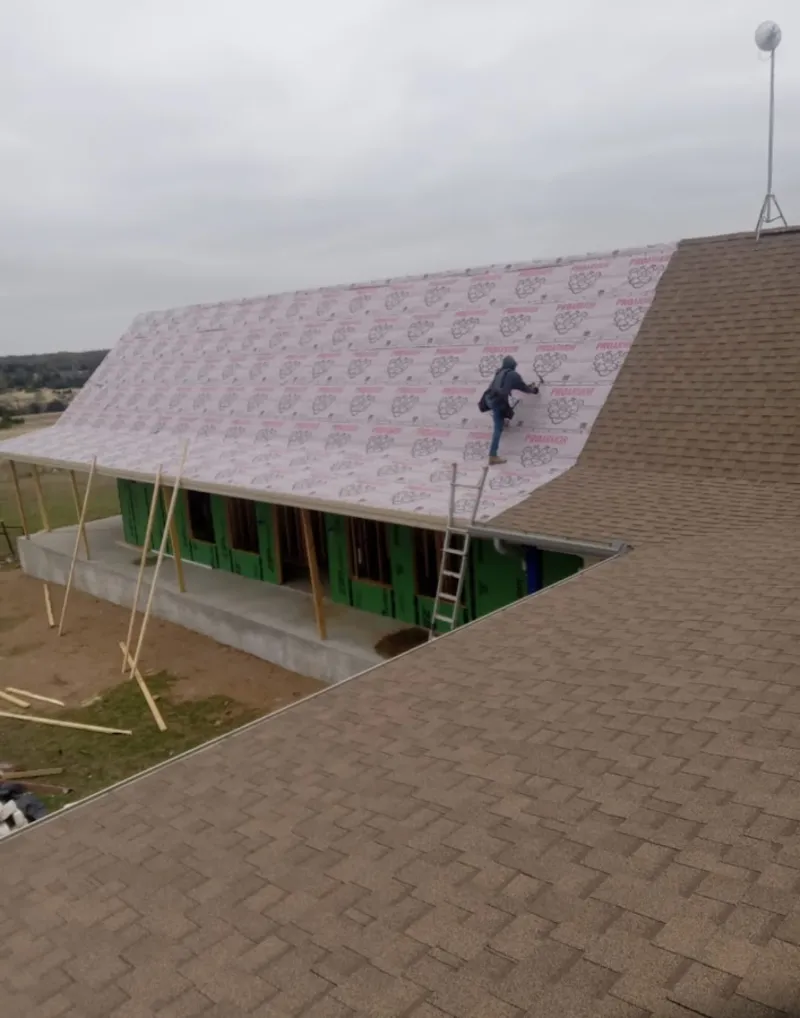 Worker preparing underlayment for a metal roof installation in Waterloo